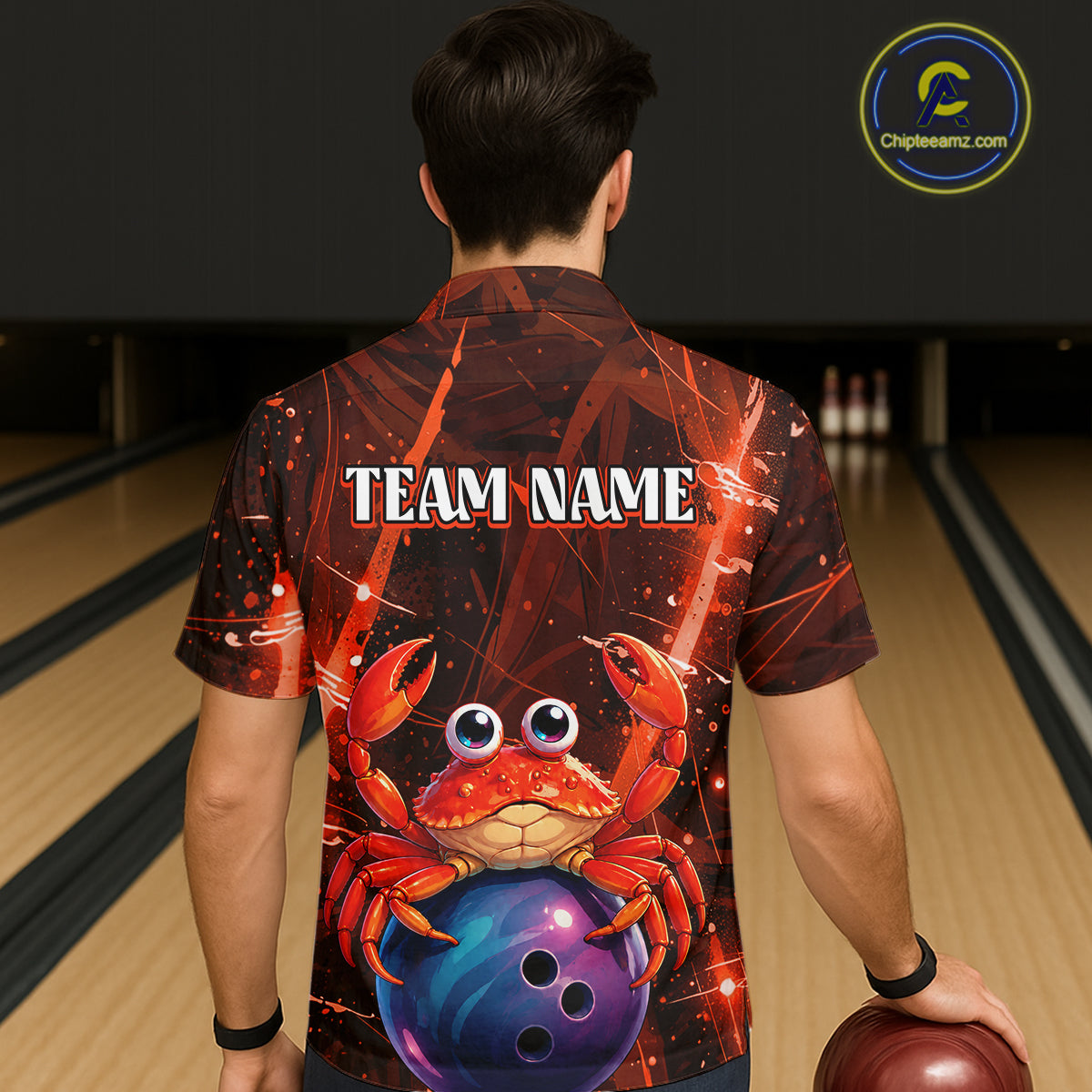 Person wearing a bowling shirt with a red crab and blue ball design, standing in a bowling alley.