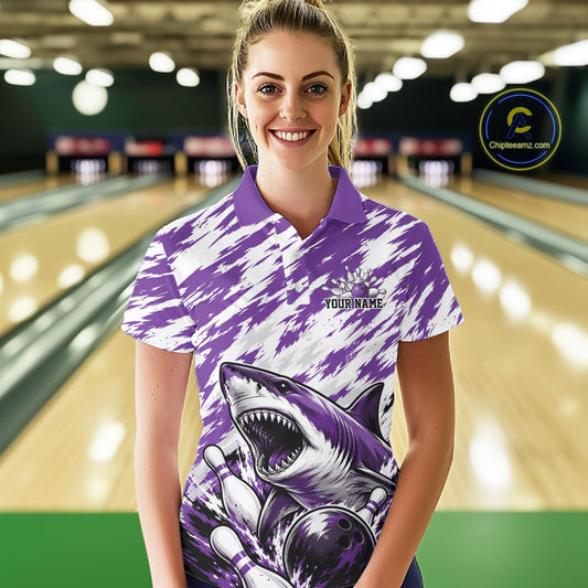 Woman wearing a purple and white bowling shirt with a shark design in a bowling alley.