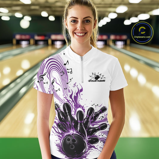 Female model wearing a white and purple bowling quarter-zip shirt at the bowling lane with musical wave graphics and bowling artwork.