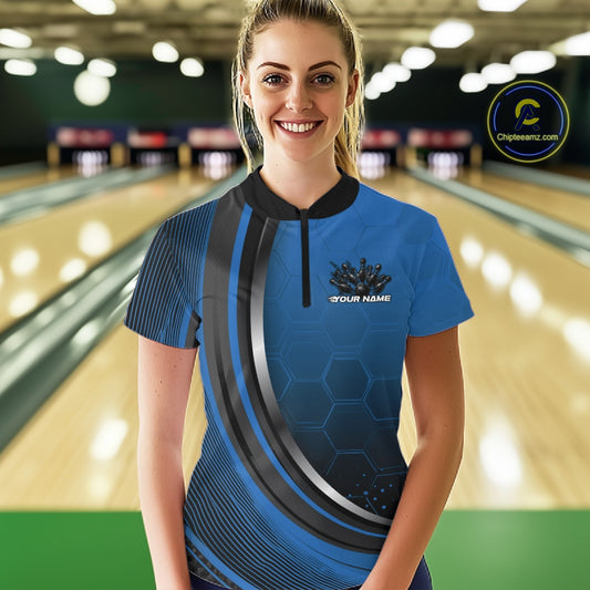 Female model at the bowling lane wearing a black and blue bowling quarter zip with honeycomb artwork and a flaming bowling action scene.