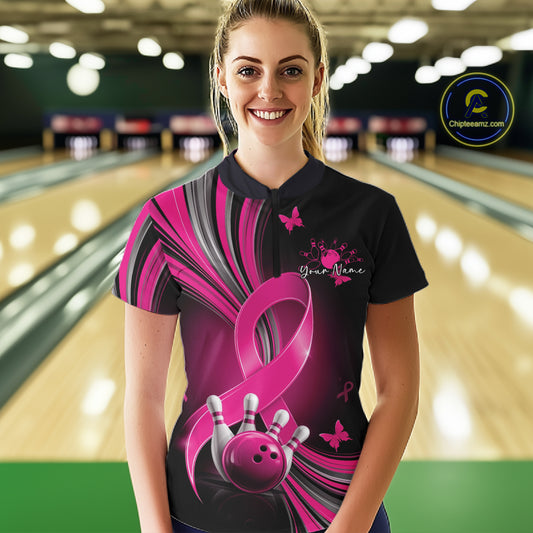 Female model wearing a black and pink bowling quarter zip with pink ribbons, small butterflies, and bowling artwork, front view