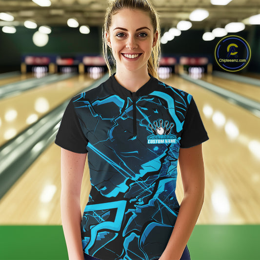 Female model in a bowling lane wearing a black and blue quarter-zip with futuristic geometric artwork.