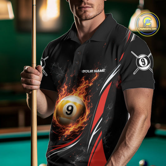 A man wearing a black short-sleeve polo shirt with a fiery billiards graphic on the front, holding a pool cue in a dimly lit pool hall. The shirt features a 9-ball design with flames