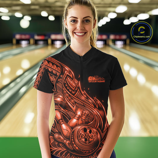 Female model wearing a black and orange bowling quarter-zip shirt at the bowling lane with Polynesian-style tribal flame graphics.