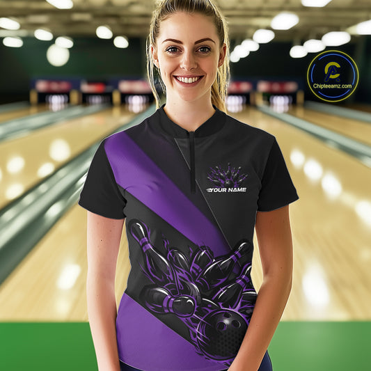 Female model front view in bowling alley wearing black and purple quarter zip shirt with flame bowling action illustration