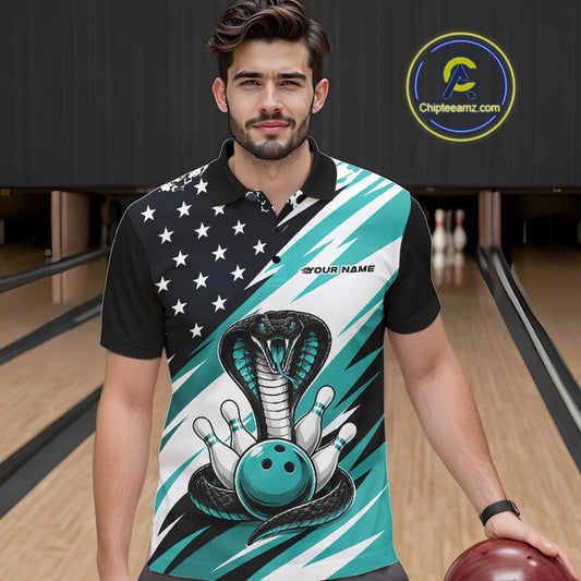 A smiling man stands in a bowling alley wearing a black, white, and blue bowling shirt with stars, diagonal stripes, a cobra, pins, and an blue ball.