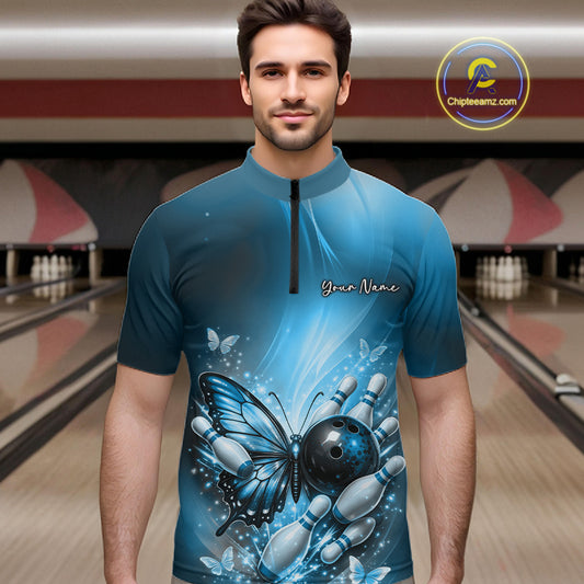 Male model wearing a blue bowling quarter-zip shirt at a bowling lane with butterfly artwork, a bowling ball, and scattered pin graphics.
