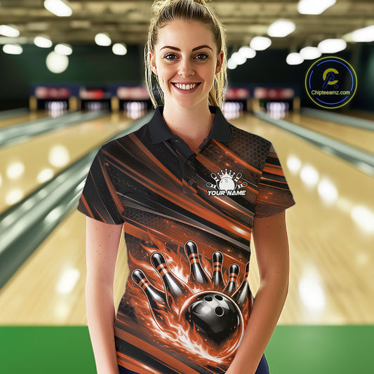 Female model wearing a black and orange bowling polo shirt at a bowling lane with bowling strike artwork and bold stripe details.