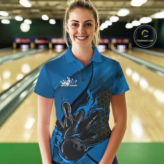 Female model at a bowling lane wearing a black and blue bowling polo shirt with bowling strike artwork and hexagonal pattern details.