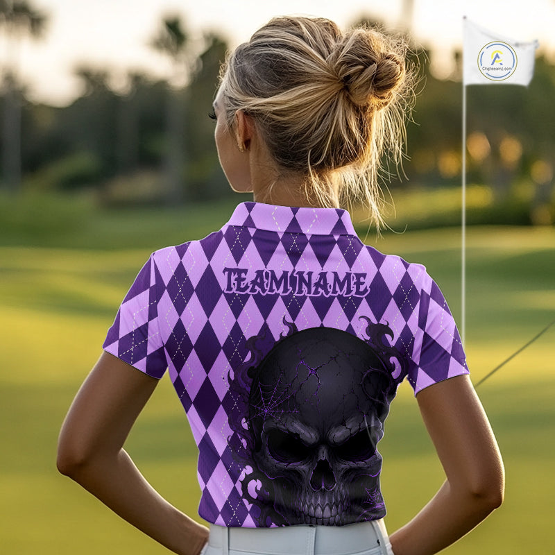 A woman on a golf course seen from behind, wearing a purple and lavender harlequin patterned short-sleeve polo shirt with 'TEAMNAME' printed across the back and a large black skull graphic. A golf flag is visible in the background.
