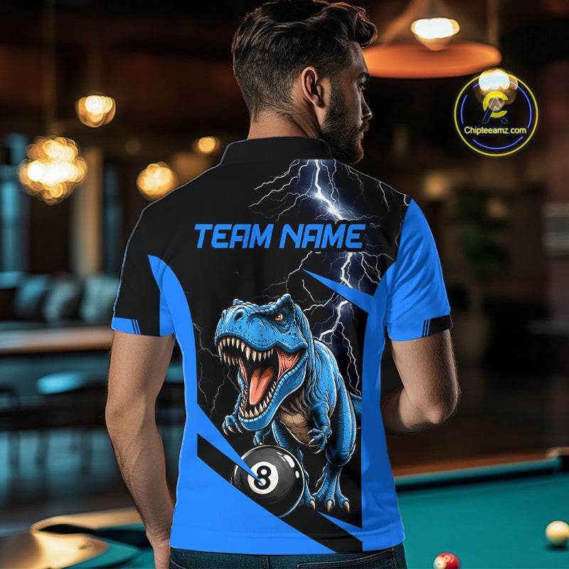 A man viewed from behind wearing a custom short-sleeve polo shirt in a billiards room. The shirt features a black and blue design with a graphic of a roaring blue T-Rex dinosaur biting a billiard ball, lightning bolts, and the text 'TEAM NAME'.