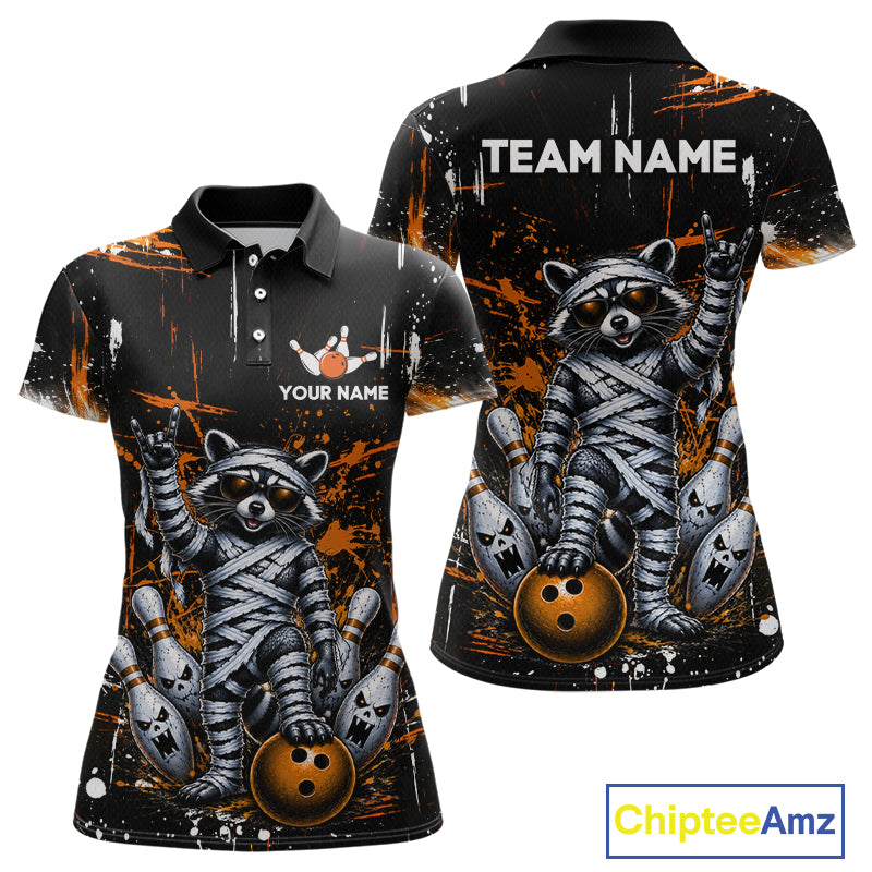 Custom short-sleeve polo shirt shown from front and back on a white background. The shirt features a black base with orange paint splatter graphics and a detailed graphic of a raccoon wrapped in bandages holding bowling balls.