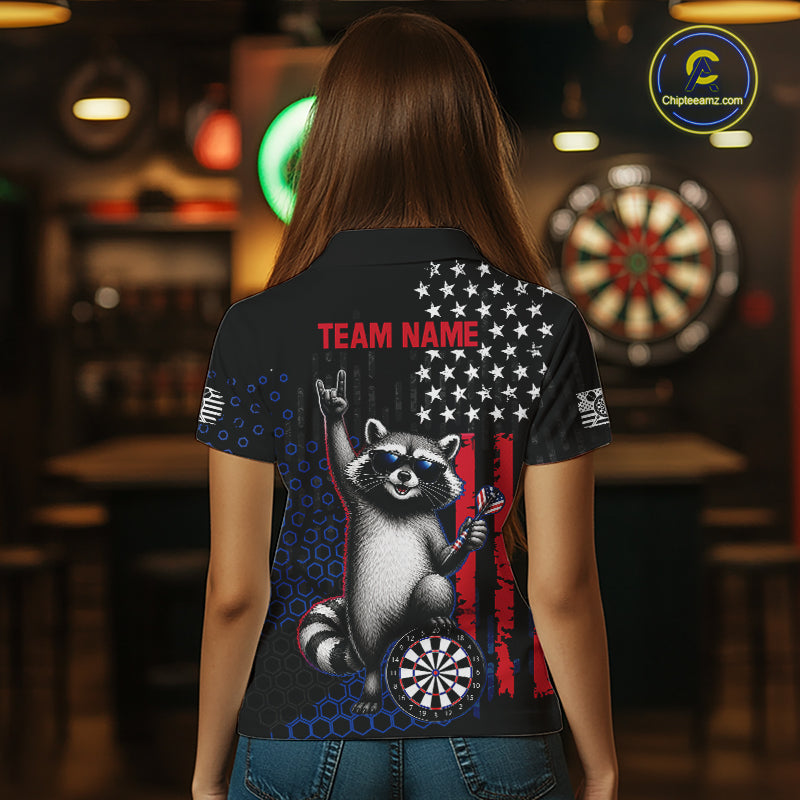 Back view of a woman wearing a custom patriotic dart polo with personalized team name and an American flag raccoon holding darts beside a dartboard in a professional dart room.