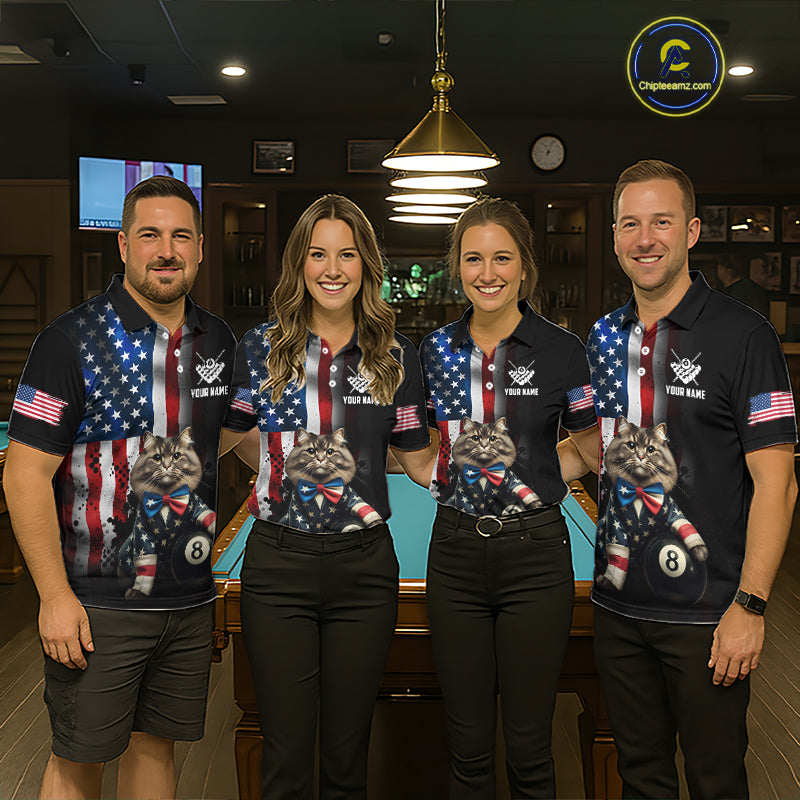 A team of four pool players stand in front of a blue felt pool table in a billiards room. All four are wearing the front view of the custom black billiards polo shirt with the distressed US flag, a cat and 8-ball motif, and 'YOUR NAME' text placeholder. 