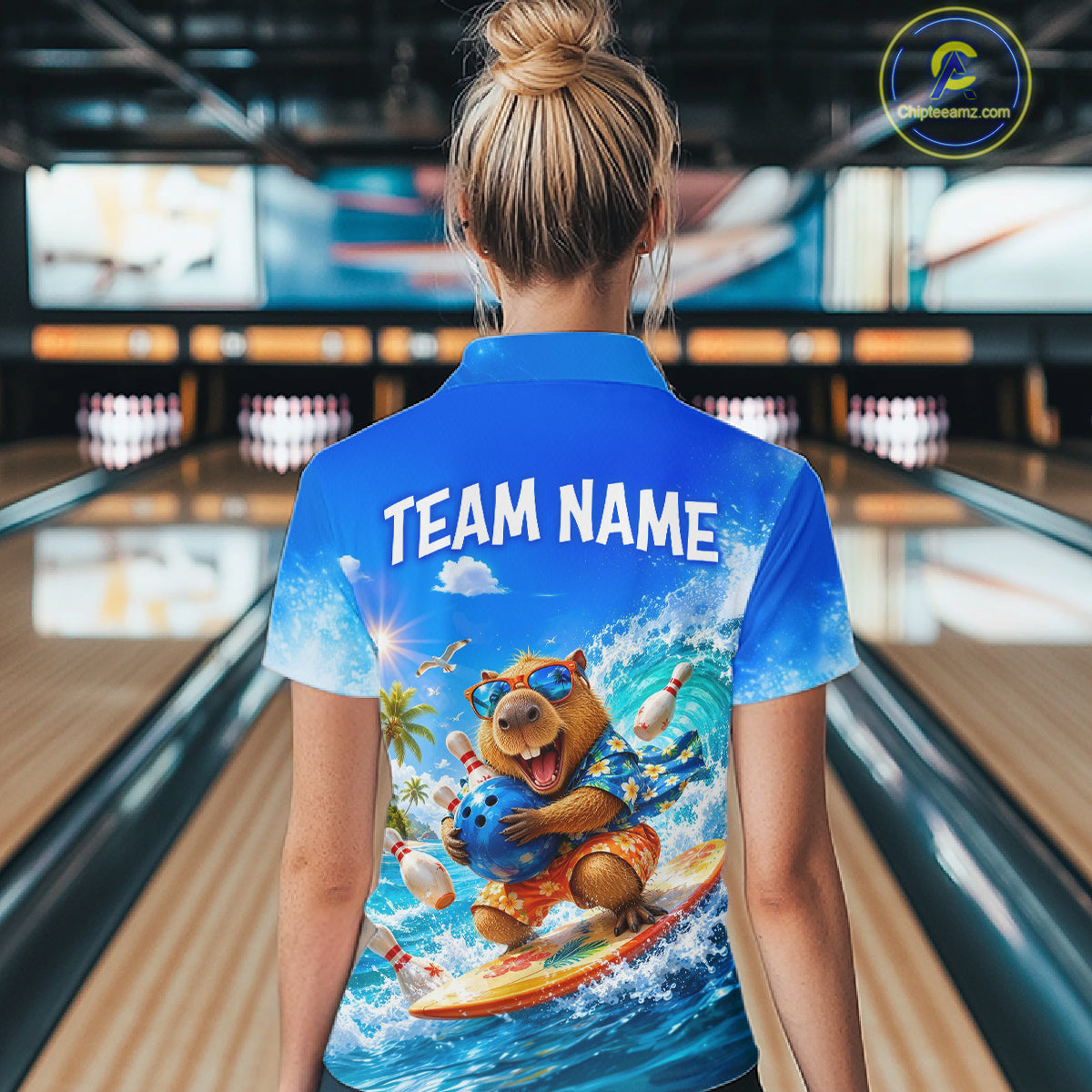 Person wearing a blue shirt with a bear graphic and 'TEAM NAME' text in a bowling alley.