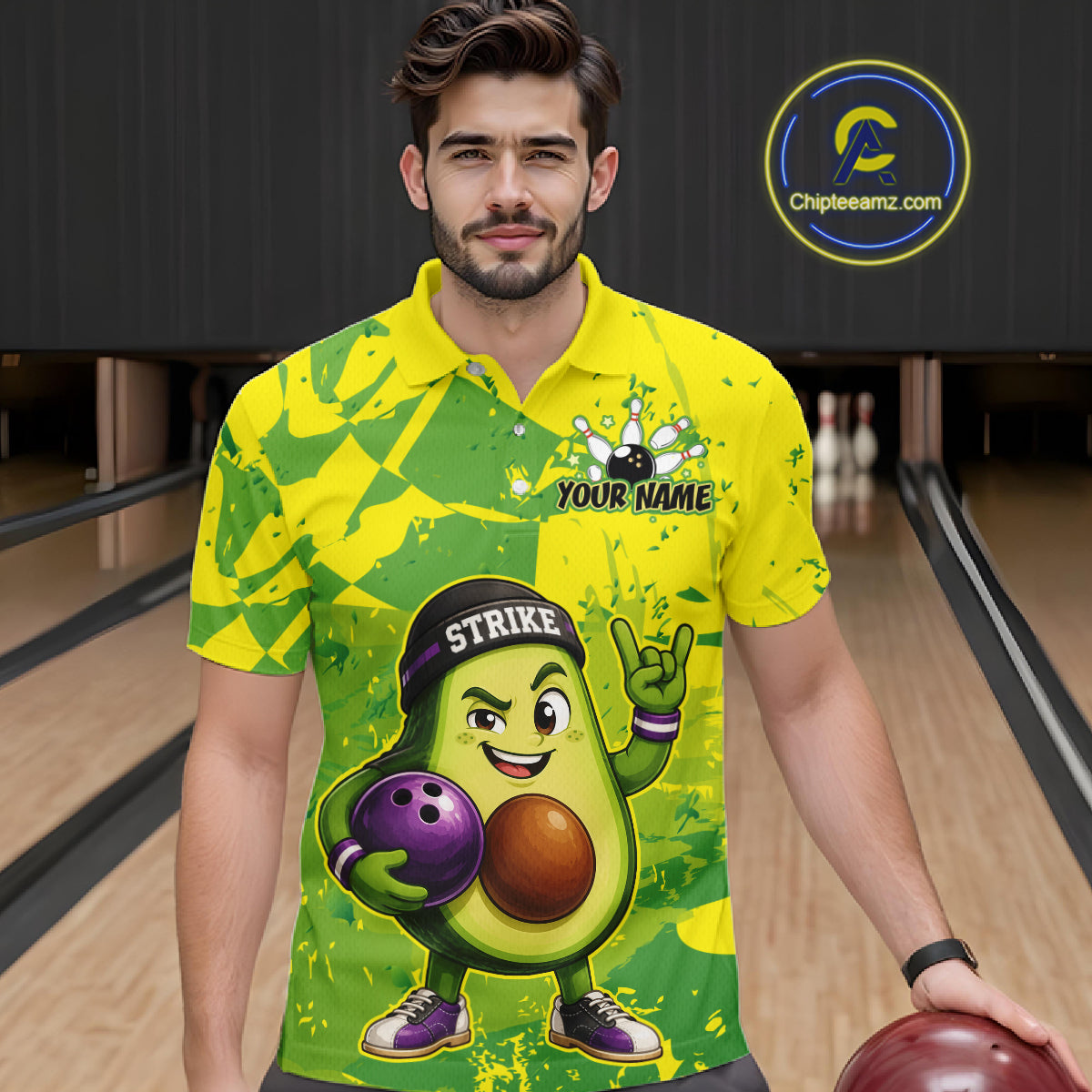 Man wearing a green and yellow bowling shirt with an avocado character holding a bowling ball in a bowling alley.