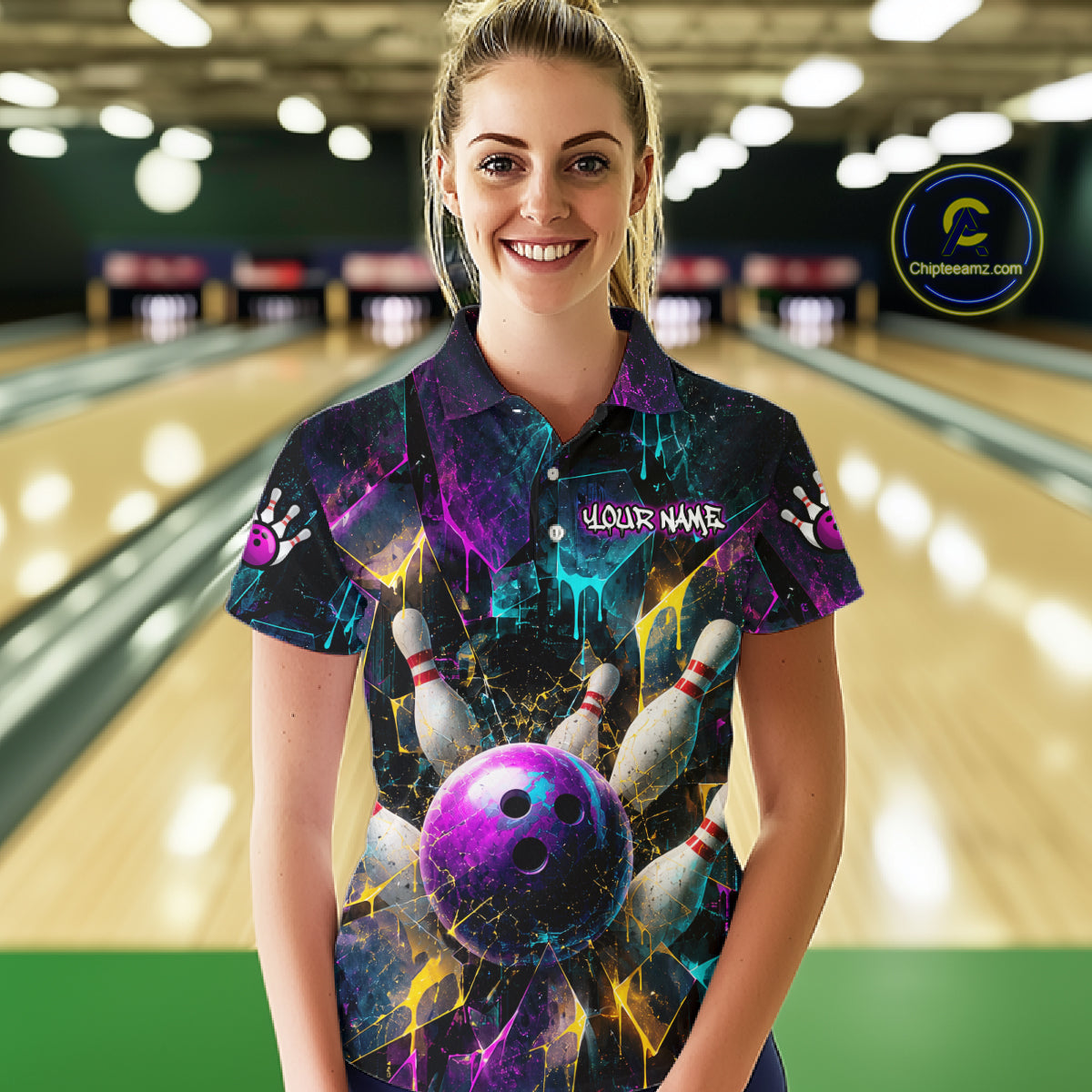A woman stands in a bowling alley wearing a short-sleeve collared shirt with a vivid bowling-themed graphic print featuring a purple bowling ball, pins, and neon cosmic colors. The shirt has a placeholder name on the chest 
