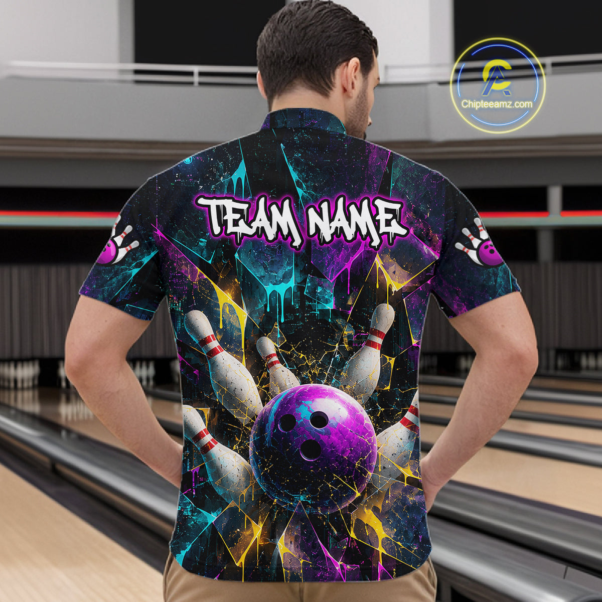 A man viewed from behind wearing a short-sleeve bowling-themed button-up shirt with a colorful cosmic design, bowling pins, and a purple bowling ball graphic. The shirt has 'TEAM NAME' printed across the back.