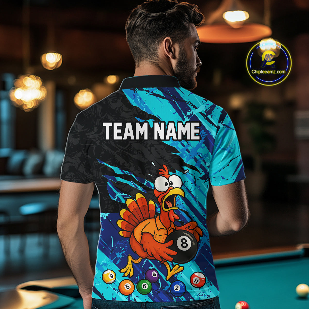 A man viewed from behind wearing a custom-designed short-sleeve polo shirt with a cartoon turkey holding an 8-ball pool bill, set against a blurred pool hall background. The shirt features a black and cyan patterned design with the text 'TEAM NAME' printed on the back.