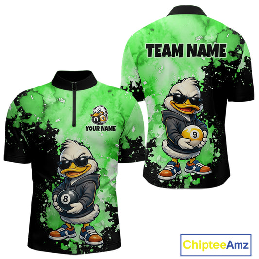 Front and back views of a short-sleeve polo shirt with a green and black watercolor splatter design, featuring a cartoon duck character wearing sunglasses and holding pool balls. The front has a half-zip collar, customizable text 'YOUR NAME', and a small logo.