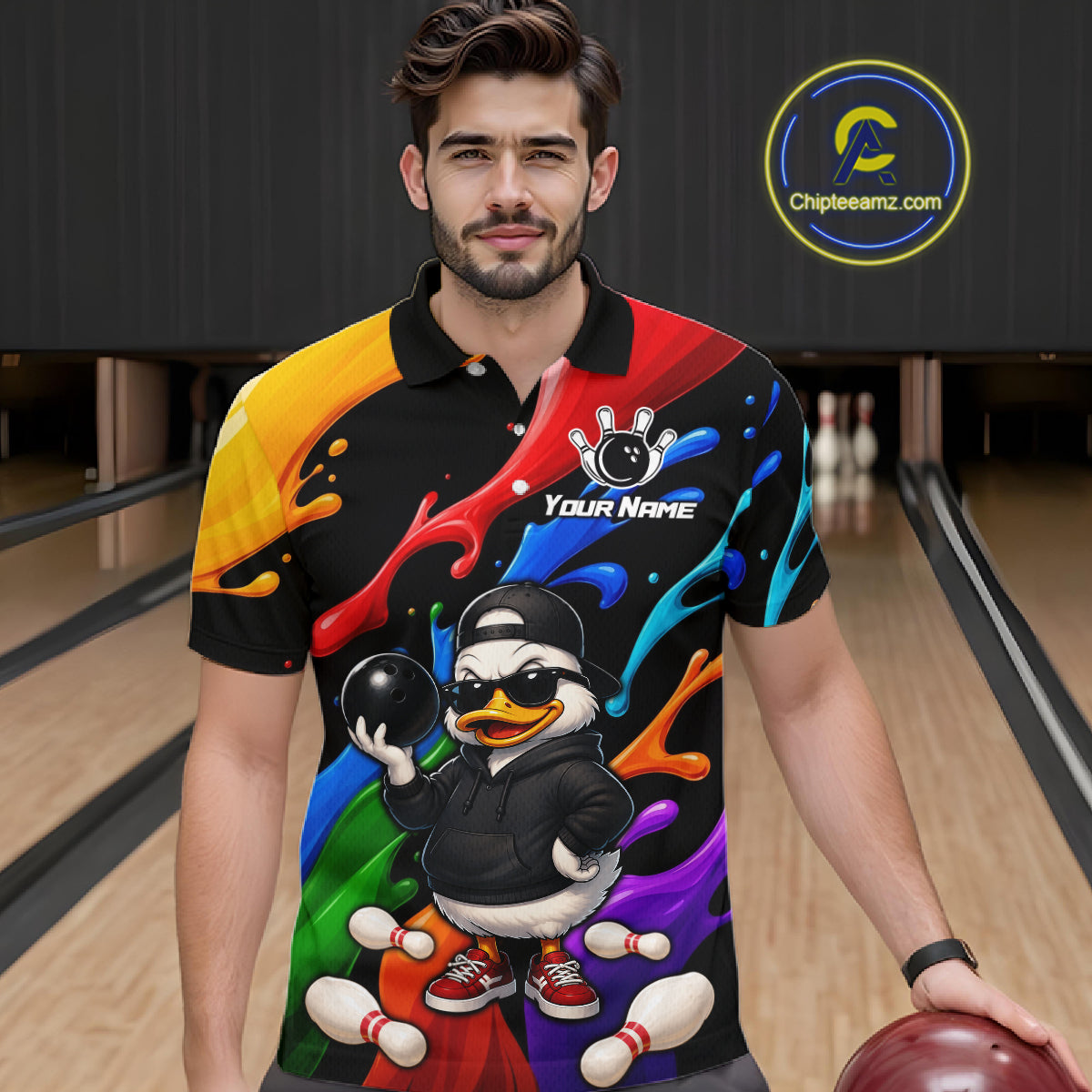 A man wearing a colorful bowling-themed custom polo shirt with a cartoon duck character graphic, standing in a bowling alley holding a bowling ball. 