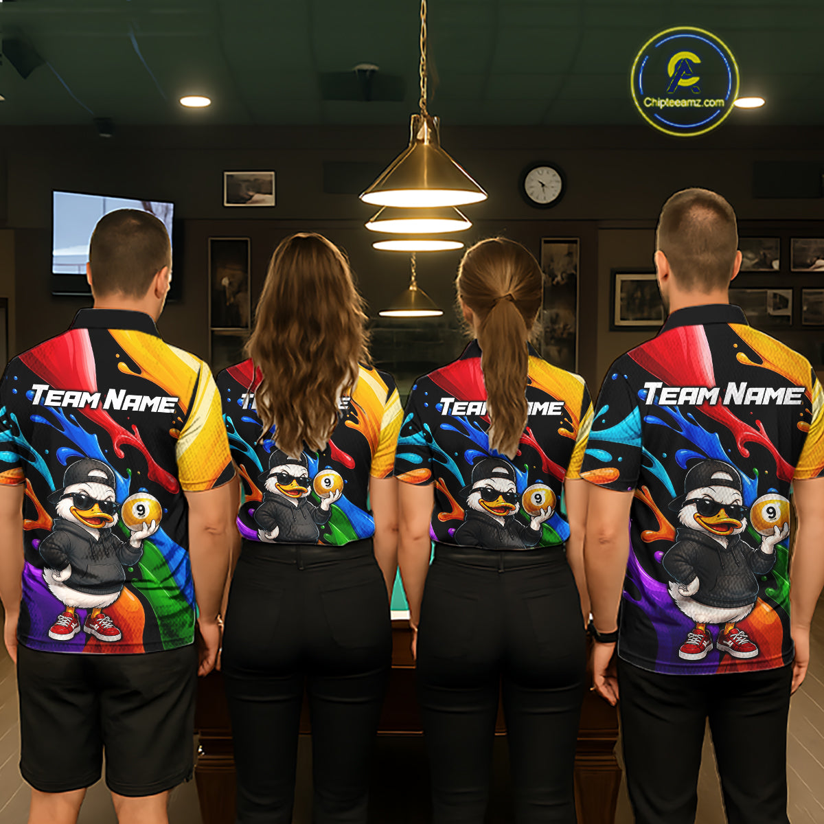 Four people standing with their backs to the camera in a dimly lit indoor venue, wearing matching team athletic jerseys with a colorful abstract background and a cartoon duck character on the back. The jerseys also feature 'TEAM NAME' text on the upper back.