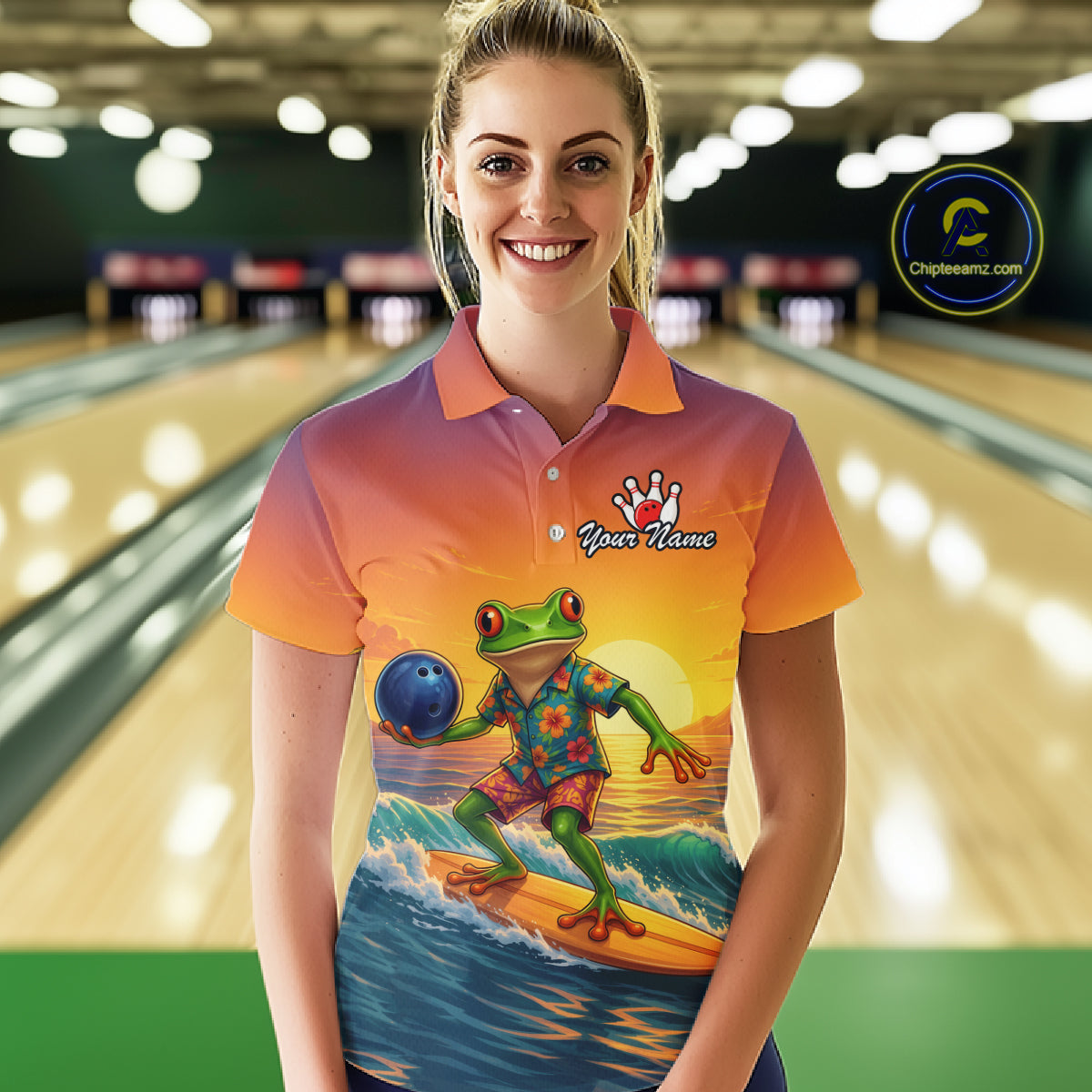 A woman stands in a bowling alley wearing a short-sleeve polo shirt with a colorful gradient background and a large graphic of a green frog surfing on a wave while holding a blue bowling ball. The shirt has a custom name print on the chest.