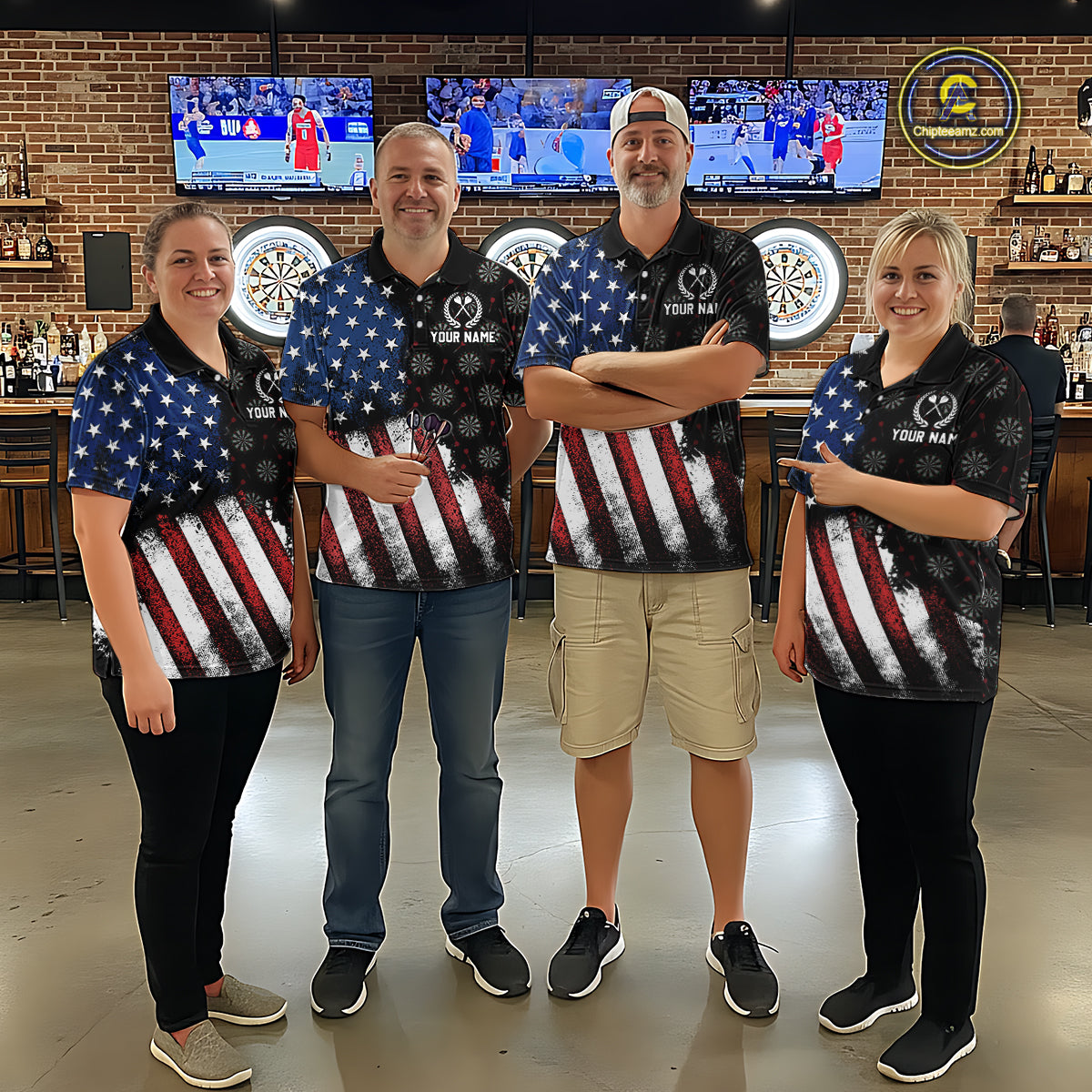 Group of darts players wearing matching custom black polo shirts with distressed US flag graphics, posing together in a sports bar setting
