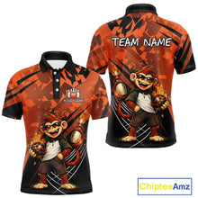 Load image into Gallery viewer, Front and back views of a short-sleeve custom polo shirt featuring a cartoon monkey graphic on an orange and black patterned background. The front shows a customizable chest logo area, while the back displays 'TEAM NAME' text at the top.