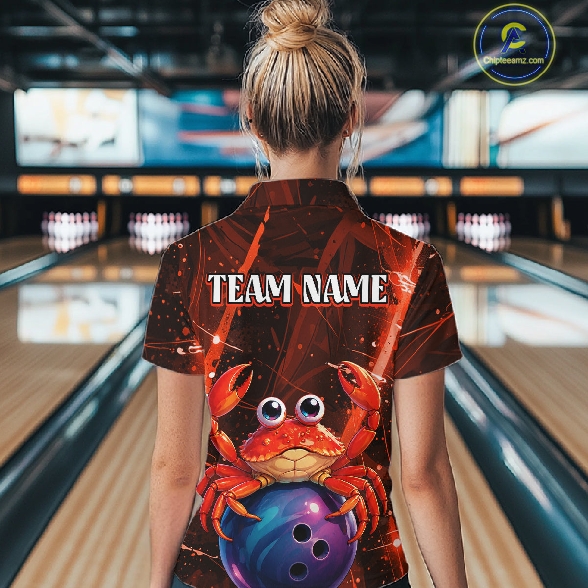 Person wearing a bowling shirt with a crab design and 'TEAM NAME' text in a bowling alley.