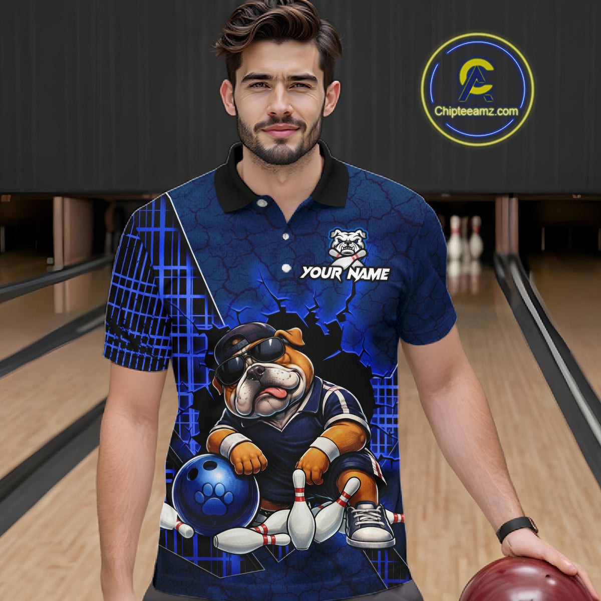 A man wearing a custom blue bowling-themed polo shirt with a bulldog graphic and 'YOUR NAME' text, standing in a bowling alley. 