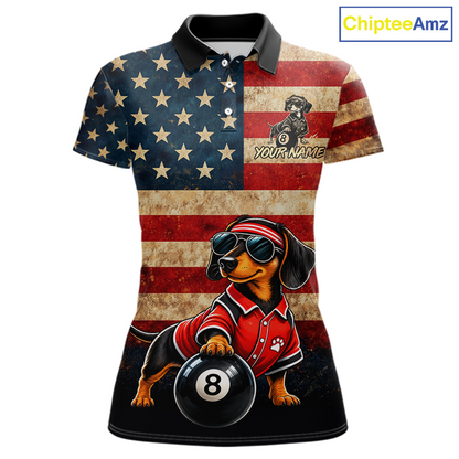 A women's short-sleeve polo shirt with a distressed American flag print on the upper body and a cartoon dachshund wearing a red polo shirt and sunglasses, holding a black 8-ball. The shirt has a black collar and cuffs, and the text 'YOUR NAME' is printed on the chest.