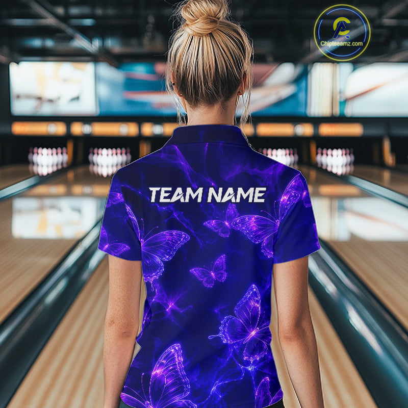 A woman viewed from behind wearing a short-sleeve collared bowling shirt with a purple and blue neon butterfly pattern and 'TEAM NAME' printed across the upper back, standing in a bowling alley.