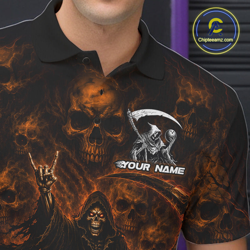 A close-up of a person wearing a black short-sleeve polo shirt with a fiery skull and grim reaper graphic print. The shirt features orange and yellow flames, skull motifs, a large scythe graphic, a hand gesture, and the customizable text 'YOUR NAME'.