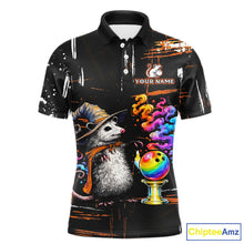 Load image into Gallery viewer, A black short-sleeve polo shirt with a colorful graphic print of a opossum in a witch hat next to a rainbow bowling ball, on a white background.