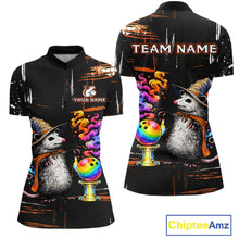 Load image into Gallery viewer, A black short-sleeve polo shirt shown from the front and back, featuring a printed design of two gray hedgehogs wearing witch hats beside colorful rainbow bowling balls on gold stands, with customizable text areas reading 'TEAM NAME' and 'YOUR NAME'. The background is plain white.