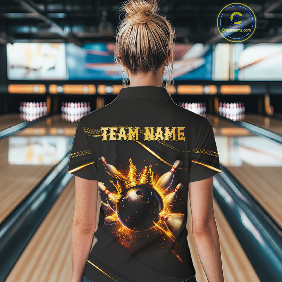 Woman wearing custom black gold bowling polo shirt back view featuring a fiery bowling ball and flame burst effect, displaying Team Name, at the bowling alley