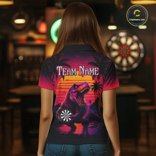 Load image into Gallery viewer, Women wearing darts polo shirt featuring a dinosaur holding a dartboard with sunset and palm tree artwork on a colorful background.