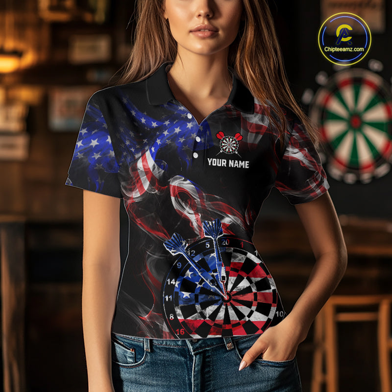 Person wearing a black darts polo featuring patriotic American flag smoke graphics, dartboards, blue darts, and custom team and player name text.