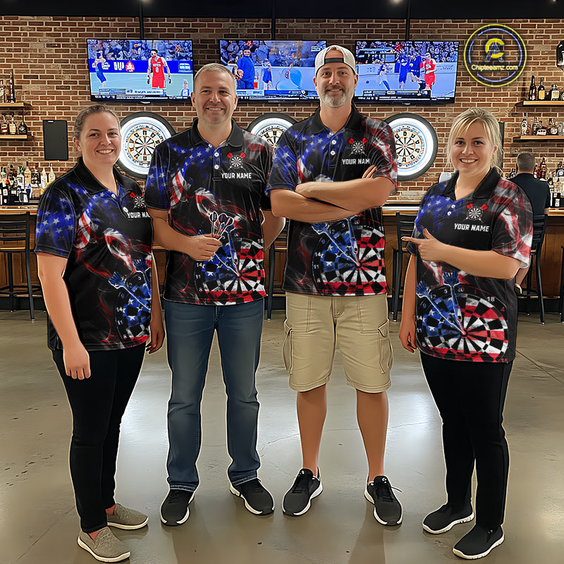 Four people wearing black darts polo featuring patriotic American flag smoke graphics, dartboards, blue darts, and custom team and player name text.
