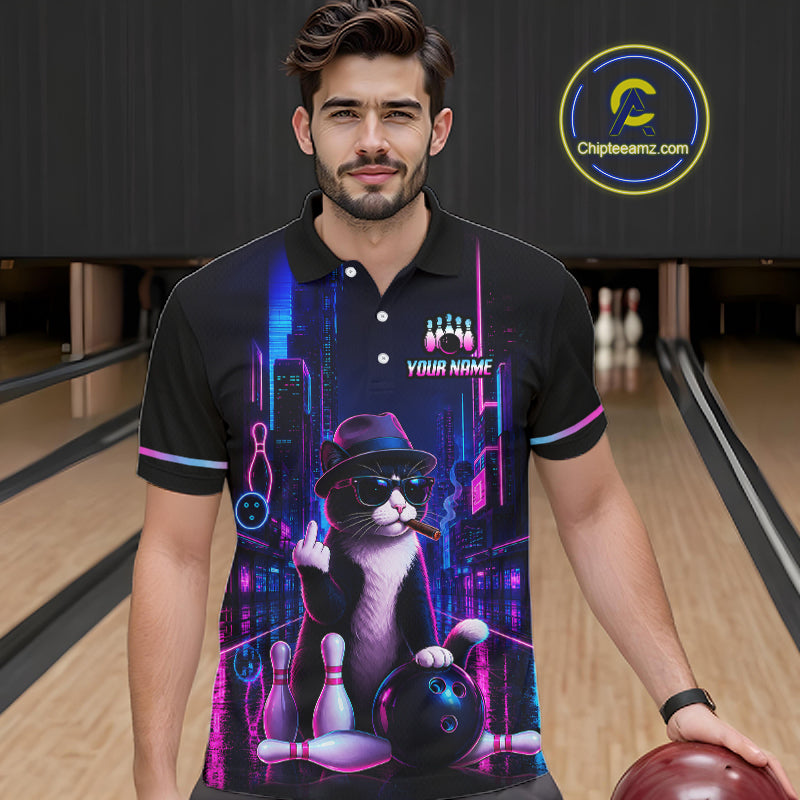 A man wearing a black short-sleeve polo shirt with a colorful graphic print of a cat bowling in a neon city setting, standing in a bowling alley. The shirt has a custom name printed on the chest.