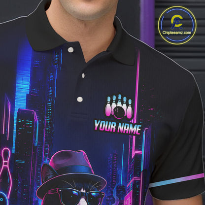 A close-up of a person wearing a black short-sleeve polo shirt with a neon cityscape bowling graphic. The shirt features a custom bowling pins and ball design above the text 'YOUR NAME' on the chest, along with a bowler character in a hat and sunglasses.