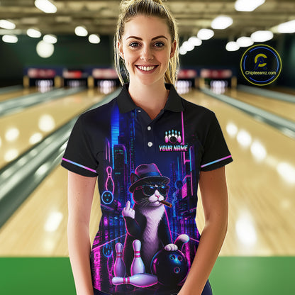 A woman stands in a bowling alley wearing a black short-sleeve polo shirt with a colorful neon cat graphic on the front. The shirt features a cat wearing a hat and sunglasses with bowling pins and a bowling ball, plus the text 'YOUR NAME' and 'Chipteeamz' on the chest and as a logo watermark.