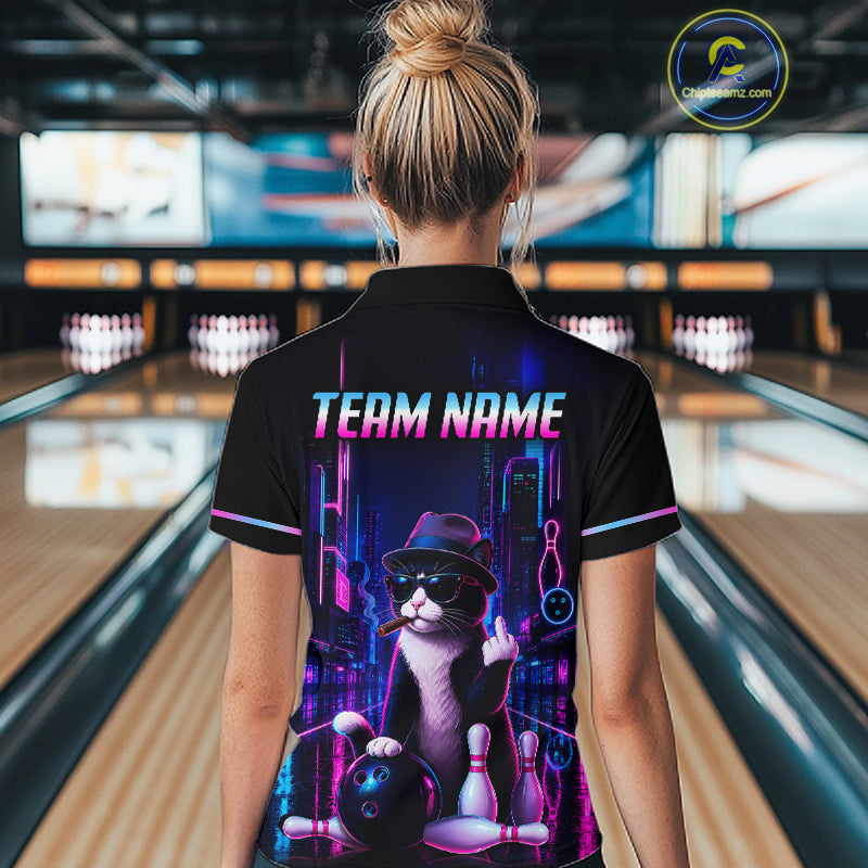 A woman viewed from behind wearing a black short-sleeve bowling shirt with a colorful neon cat graphic and the text 'TEAM NAME' on the back, standing in a bowling alley.
