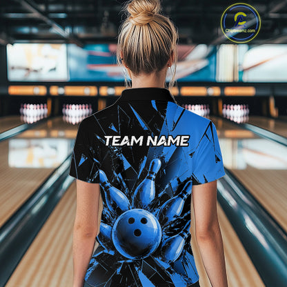 A woman viewed from behind wearing a black and blue bowling-themed short-sleeve polo shirt with a large bowling ball graphic and the text 'TEAM NAME' on the back, standing in a bowling alley.