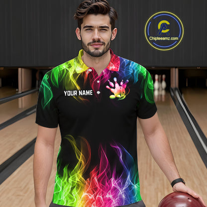 A man wearing a black short-sleeve bowling shirt with a vibrant rainbow flame and lightning print, standing in a bowling alley. The shirt features a white customizable name placeholder on the chest and a colorful bowling pin graphic.