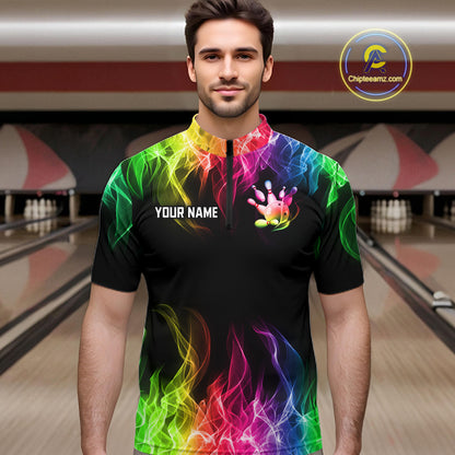 A man wearing a black short-sleeve bowling jersey with a vibrant rainbow flame pattern and a bowling pin graphic on the chest, set against a blurred bowling alley background.