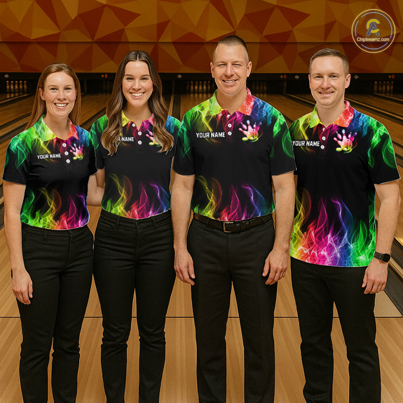 Four people standing in a bowling alley wearing matching black short-sleeve bowling shirts with a vibrant multicolor flame and handprint graphic. The shirts have customizable text on the chest.