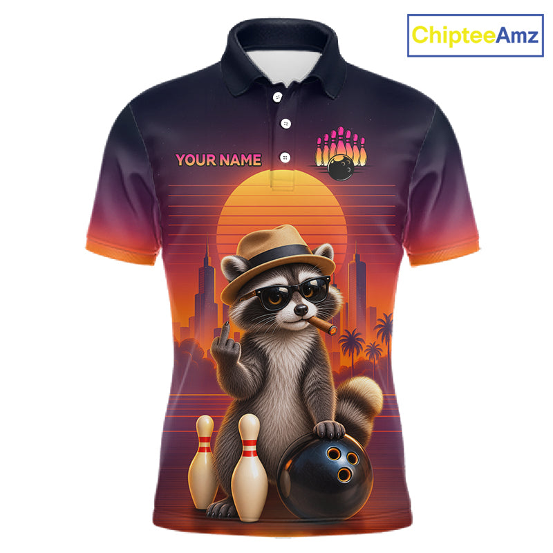 A short-sleeve polo shirt with a dark navy-to-orange gradient background and a large retro-style raccoon graphic on the front. The raccoon wears a hat and sunglasses and poses with bowling pins, bowling balls, and bowling pins against a sunset cityscape.