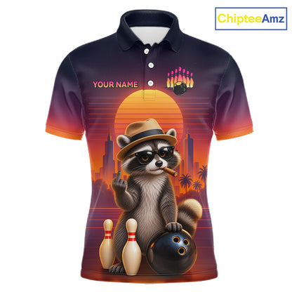 A short-sleeve polo shirt with a dark navy-to-orange gradient background and a large retro-style raccoon graphic on the front. The raccoon wears a hat and sunglasses and poses with bowling pins, bowling balls, and bowling pins against a sunset cityscape.